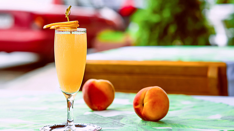 Bellini cocktail on table next to whole peaches at bar's outdoor terrace downtown