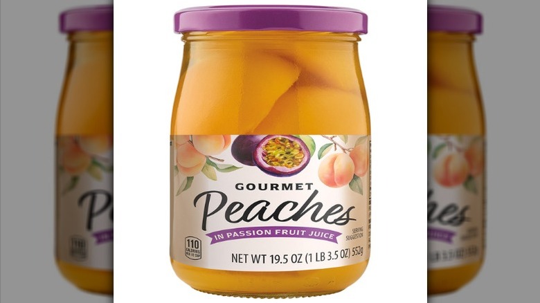 Glass jar of Aldi Specially Selected Gourmet Peaches in Passion Fruit Juice on a white background.