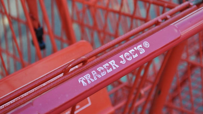 Sign of Trader Joe's in the handle of red shopping cart.