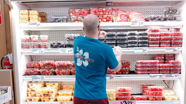 Grocery store worker stocking shelves with fresh fruit