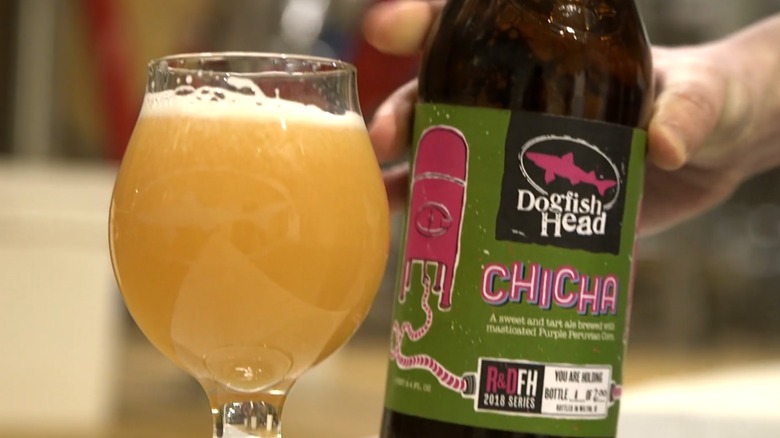 A close-up of a bottle of Dogfish Head Chica beer being held beside a filled glass