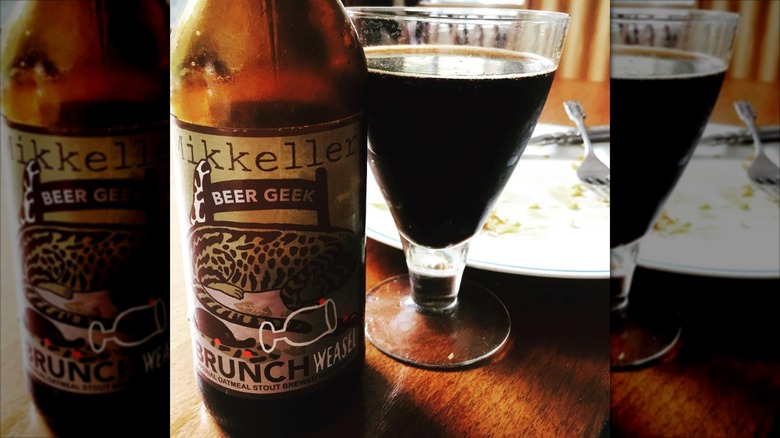 Mikkeller Beer Geek Brunch Weasel bottle beside a glass cup filled and sitting on a table
