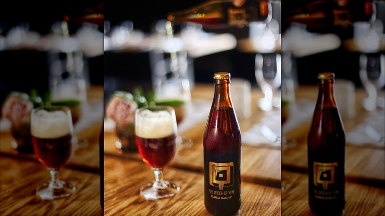 Bottle and filled glass of The Order of Yoni Bottled Instinct beer