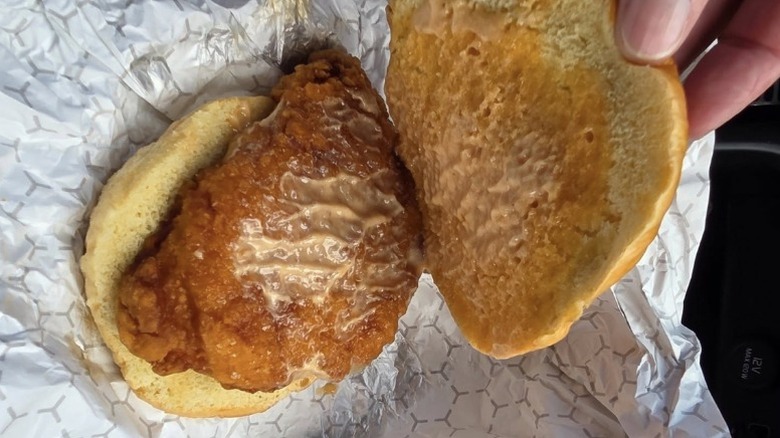 Hand pulling off top bun of Buc-ee's fried chicken sandwich