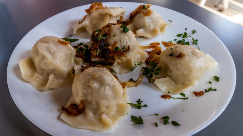 Typical Polish dish of potato and cheese pierogi on a plate with toppings