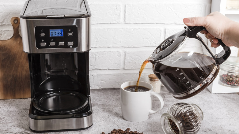Woman pouring coffee from a drip coffee machine