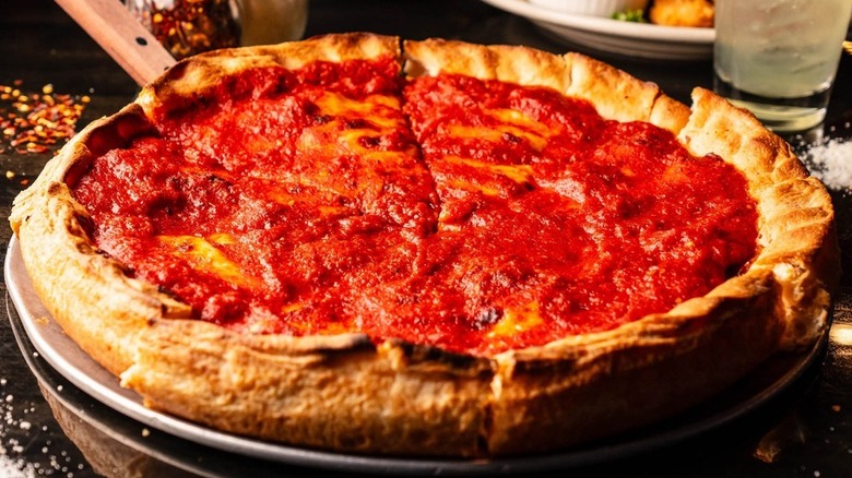 A Chicago-style deep dish pizza sliced resting on a metal tray