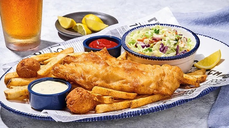 Red Lobster fish and chips on a platter on newspaper with a side of cole slaw and tartar and cocktail sauce.