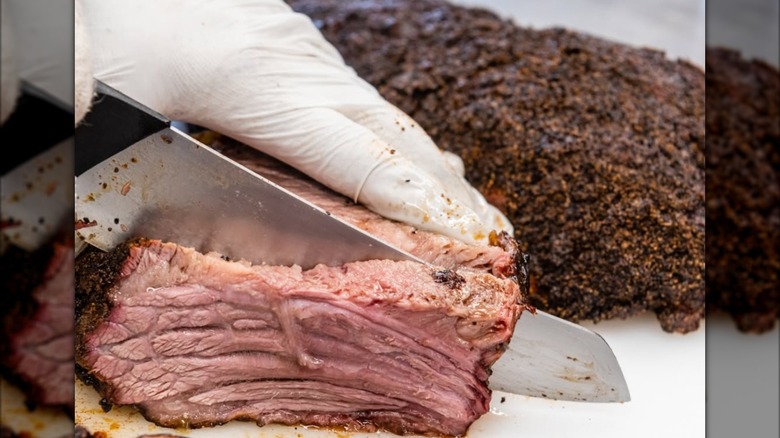 Gloved hand cutting brisket at Roy's Meat Service