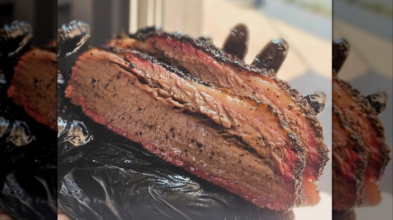 Gloved hand holding sliced brisket at Stoke Haus Brewing & Barbecue