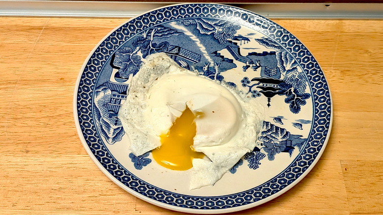 A microwaved fried egg on a plate cut open so the runny yolk is visible.