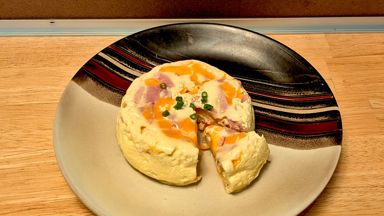 A microwaved frittata filled with ham, cheese, and green onion on a plate
