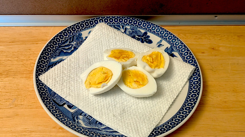 A microwaved hard-boiled egg on a plate cut open so the yolk is visible