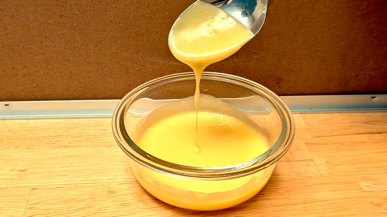 A microwaved hollandaise sauce with a spoon that has been dipped into it