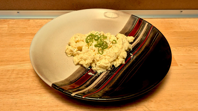 A plate of microwaved scrambled eggs topped with pepper and green onion