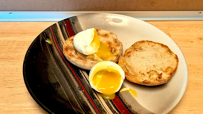 A microwaved soft-boiled egg on a plate cut open so the runny yolk is visible with an English muffin