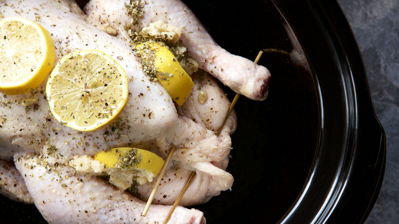 Whole raw chicken with lemon and garlic in slow cooker