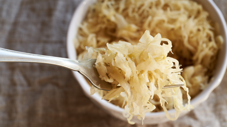 Homemade sauerkraut on a fork in a white bowl