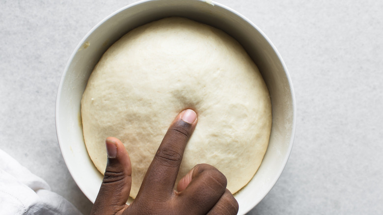 Checking if dough is proofed using a finger, process of making bread