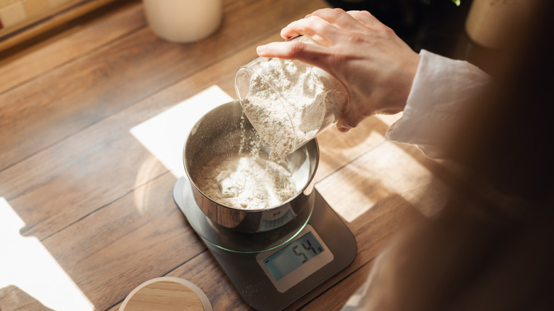 Measuring flour with electronic kitchen scales for cooking something.