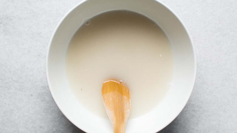 Overhead view of Instant dry yeast sprinkled on warm water, top view of dry yeast granules dissolved in water
