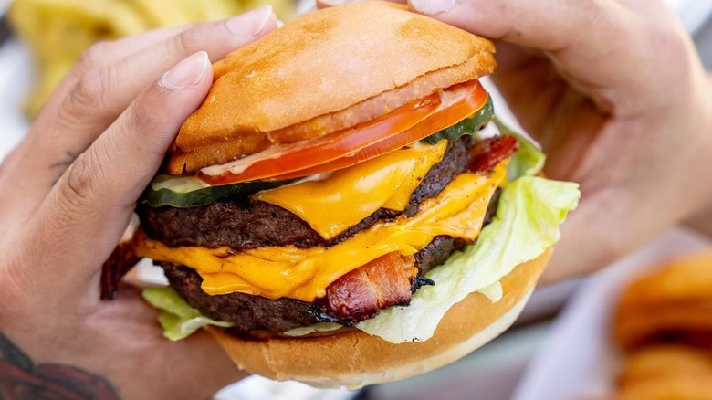 Hands holding a Double Cheeseburger with bacon from Gott's Roadside