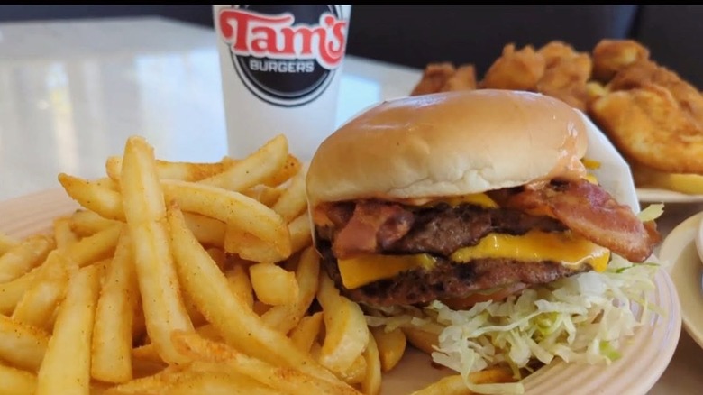 Cheeseburger with side of fries and drink in the background from Tam's Burgers