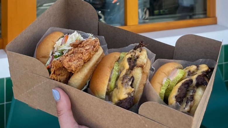 To-go box with a chicken sandwich and two cheeseburgers from the Win~Dow