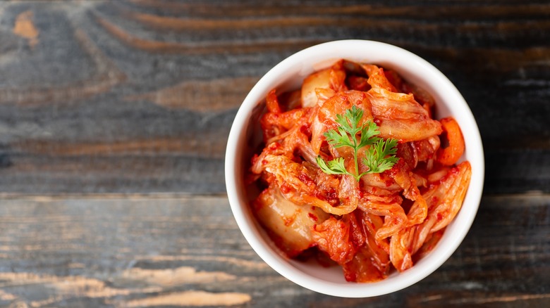 Kimchi cabbage in a bowl on wooden background, top view, Korean food