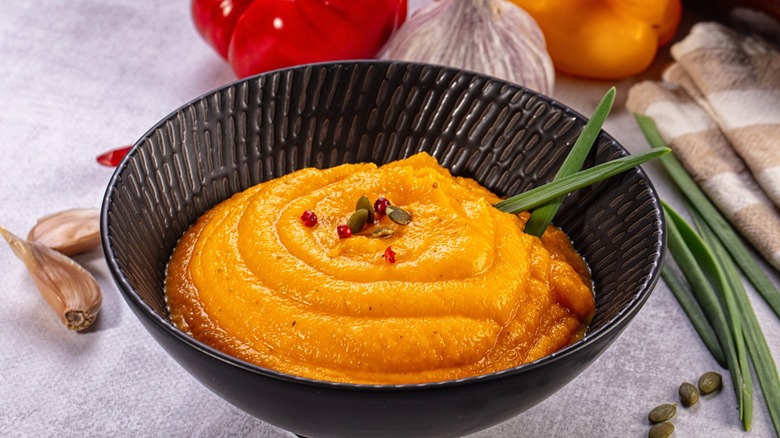 Vibrant orange sweet potato puree swirled in textured black bowl.