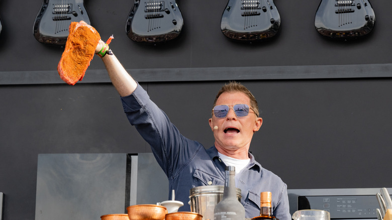 Bobby Flay holding a seasoned steak aloft