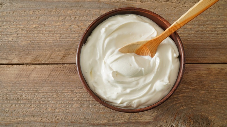Crème fraîche in bowl with wooden spoon on wooden table