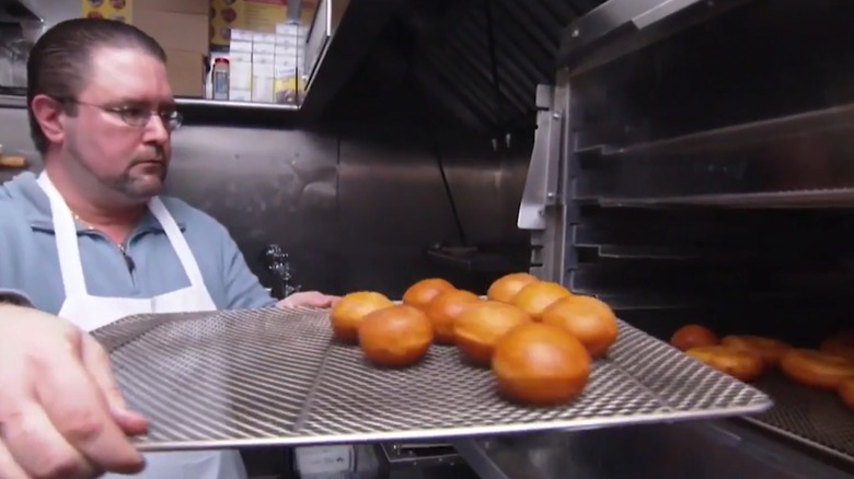 A screen shot of David Ruggerio holding a tray of pastries in an industrial kitchen