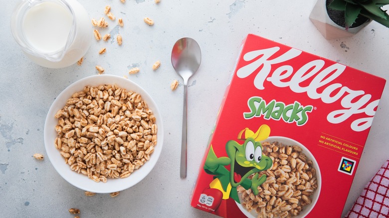 Kellogg's Smacks rice honey cereal for breakfast in bowl with spoon and milk jar on kitchen table
