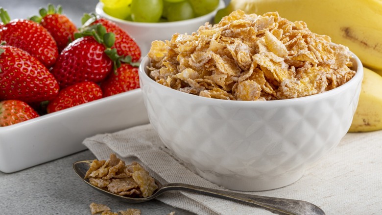 Corn flakes in the bowl with berries on the table.