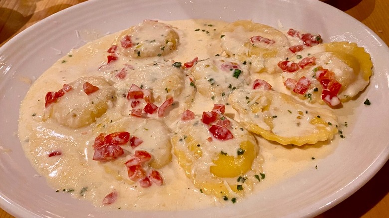 round lobster ravioli in cream sauce topped with diced tomatoes and herbs on table at Carrabba's Italian Grill