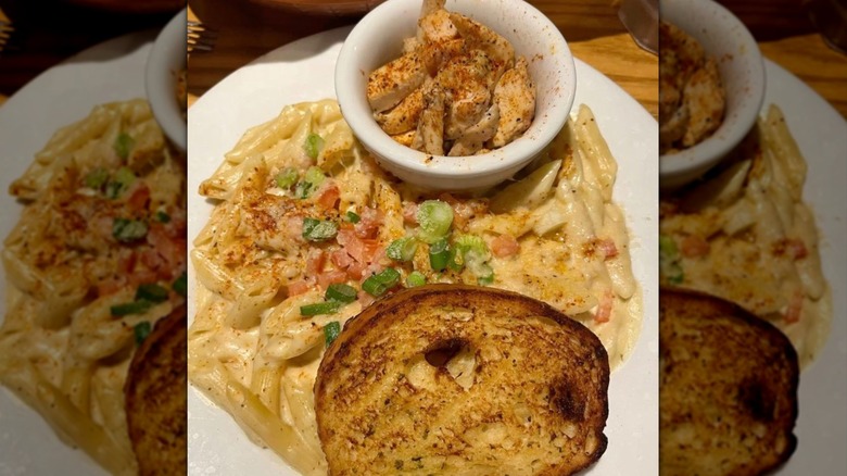 penne pasta from Chili's with cajun cream sauce, diced tomatoes, and green onions. chicken and toast on the side.