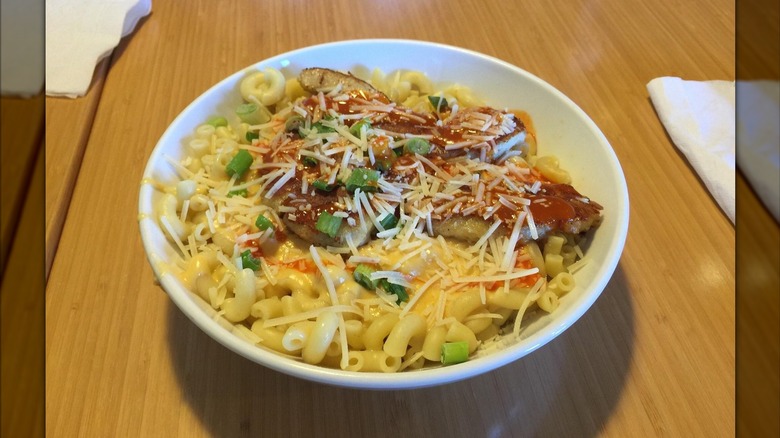 mac and cheese with buffalo chicken pieces, parmesan, and green onions on top on table at Noodles and Company