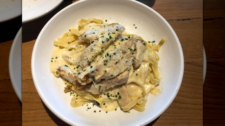 fettuccine alfredo with chicken and parmesan cheese on top on table at Olive Garden