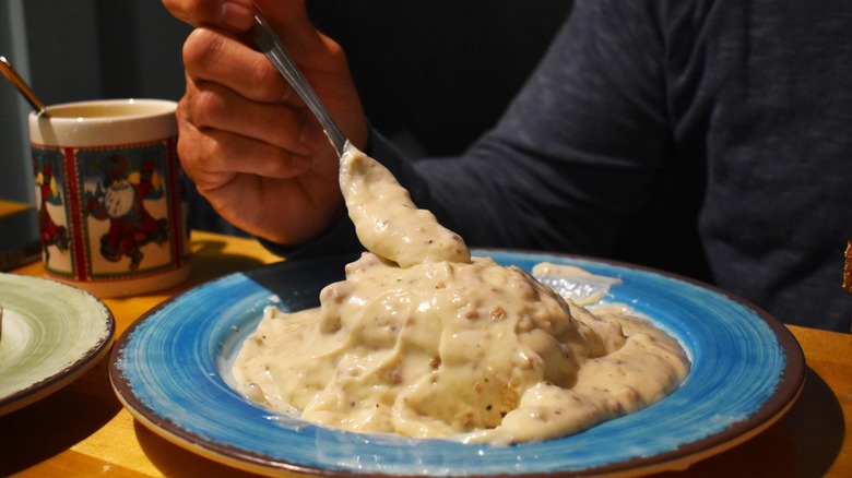 Diner shown eating biscuits and country gravy at a cafe