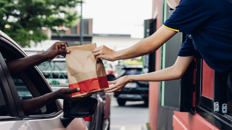 fast food drive-thru worker handing bag to customer