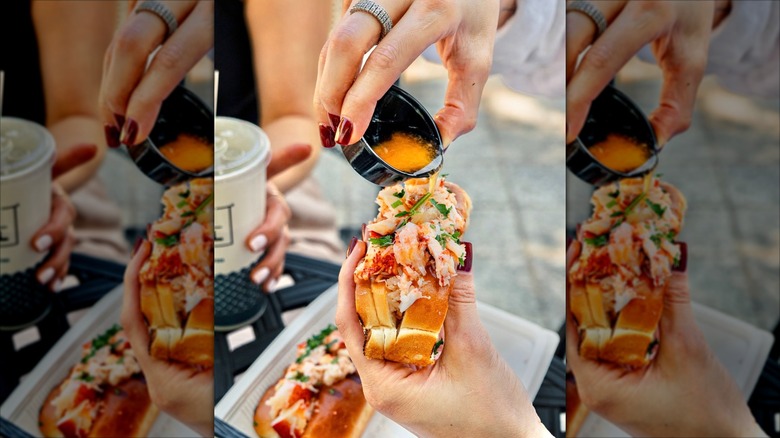 Hand shown pouring warm liquid butter on a lobster roll at California Fish Grill