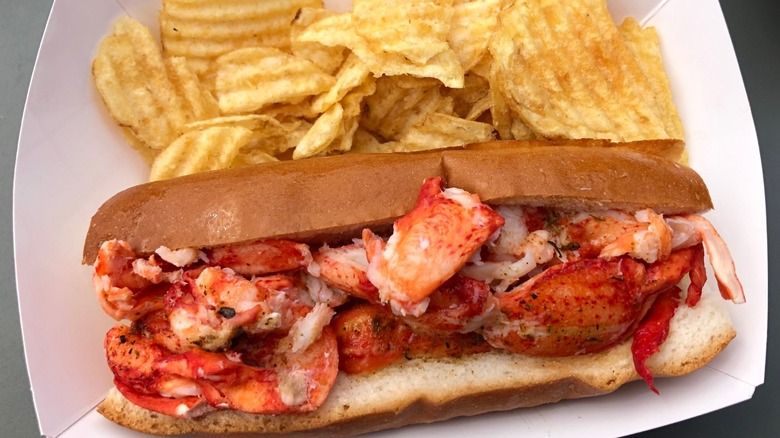 Classic lobster roll with chips in a cardboard tray