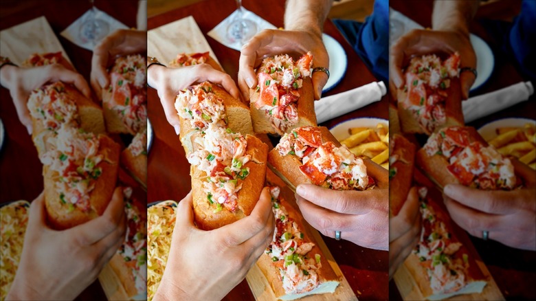 two pairs of hands holding two lobster rolls at Legal Sea Foods