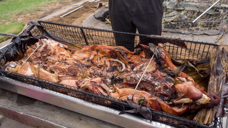 Whole cooked pig freshly removed from an underground pit