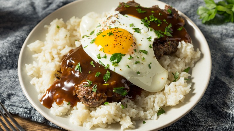 Hawaiian loco moco with hamburger, gravy, rice, and a fried egg on a white plate