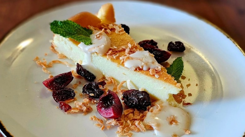 White plateful of Quilly cheesecake with dried fruit and a cookie crumble garnish