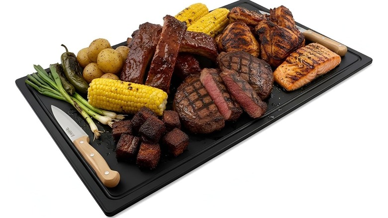 Black Thirteen Chefs grooved cutting board filled with assorted grilled meats and vegetables