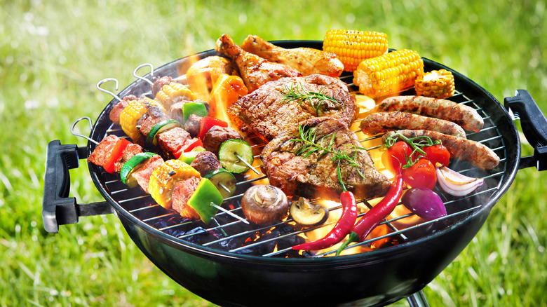 A charcoal grill with steaks, sausages, kabobs, and grilled vegetables