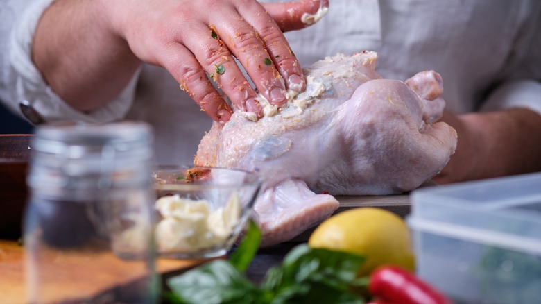 A man rubs chicken with cowboy butter.